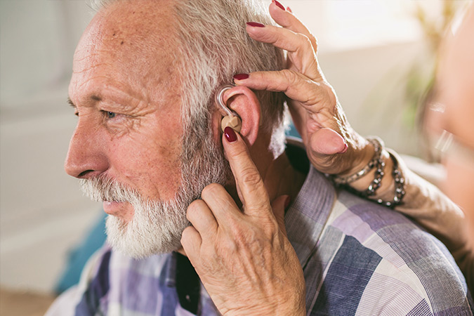 An elderly man getting fitted for a hearing aid.