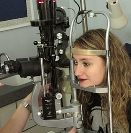 Woman taking a vision test by resting her head on the machinery.