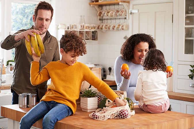 Family enjoying time in the kitchen with fruits and vegetables.