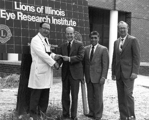 Lions of Illinois Eye Research Institute grand opening, with the founders shaking hands in front of the building.