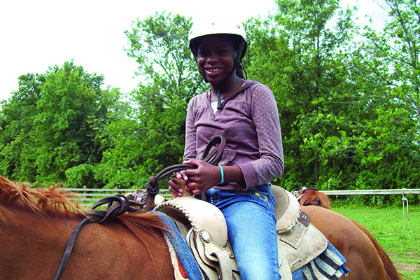 Photo of a young girl smiling on a horse at Camp Lions.