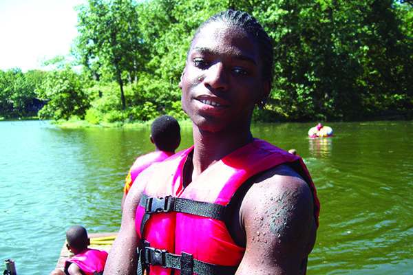 Young boy wearing a life vest right outside of a lake at Camp Lions.