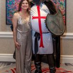 Female posing with a male dressed up as a knight with a shield.