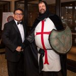 Male dressed up as a knight with a shield socializing with another member.